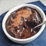 Rich and gooey chocolate pudding cake with a soft, fudgy sauce layer, served warm in a white ramekin with a spoon