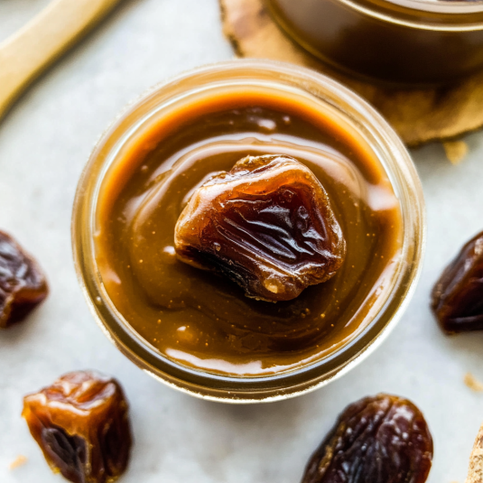 Homemade date caramel in a glass jar topped with a whole date