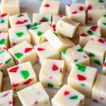 Grandmas Christmas Candy in a white bowl, featuring festive red and green gummy-filled cubes coated in creamy white chocolate