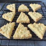 Almond shortbread cookies cut into triangle shapes cooling on a wire rack