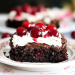 Slice of moist chocolate cherry cake topped with whipped cream and cherries
