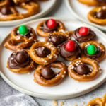 Rolo pretzels topped with melted chocolate, candy pieces, and chocolate candies on a serving plate