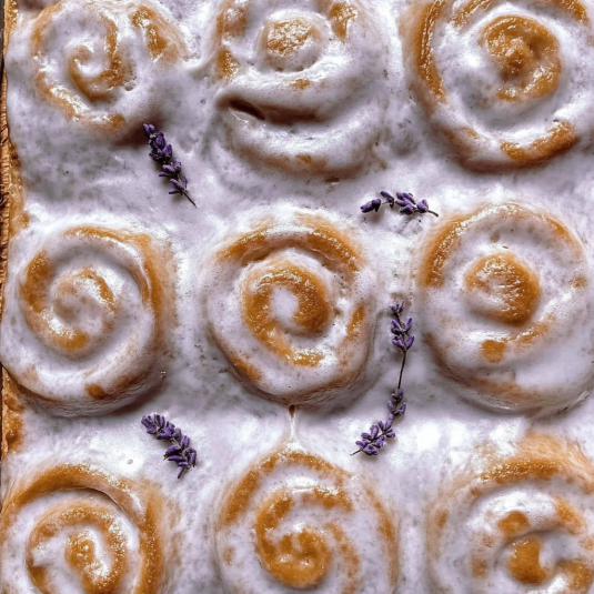 Freshly baked London Fog rolls in a square pan topped with Earl Grey vanilla glaze and lavender accents