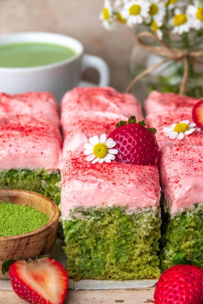 Strawberry Matcha Latte Cakes with vibrant green sponge and pink strawberry cream cheese frosting topped with fresh strawberry
