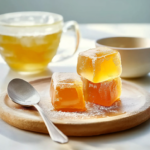Golden horse gelatin trick cubes served on a wooden plate beside a warm herbal tea drink